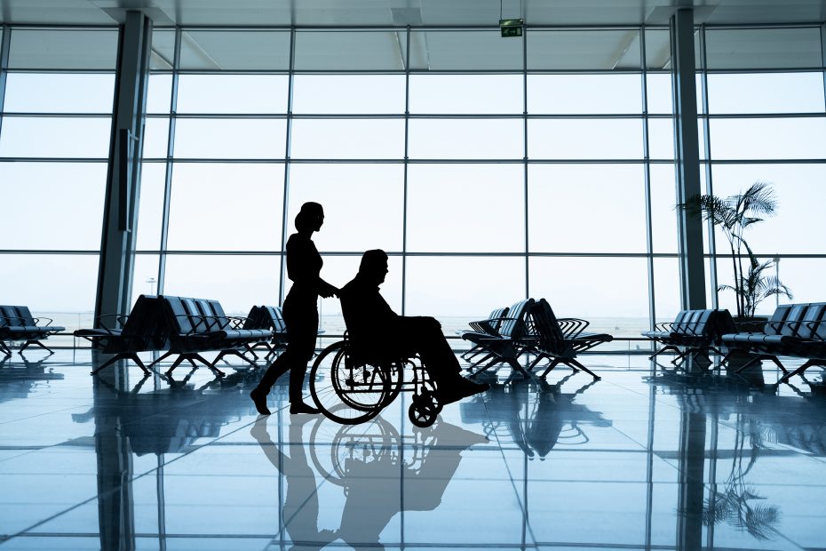 Man in a wheelchair is being taken care at the airport.